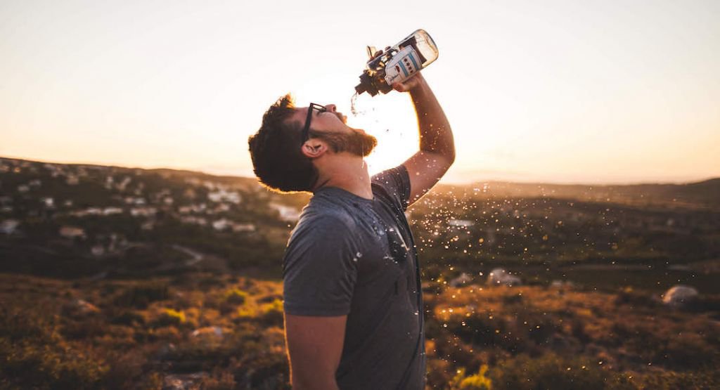 Man drinking water with background mountain scene