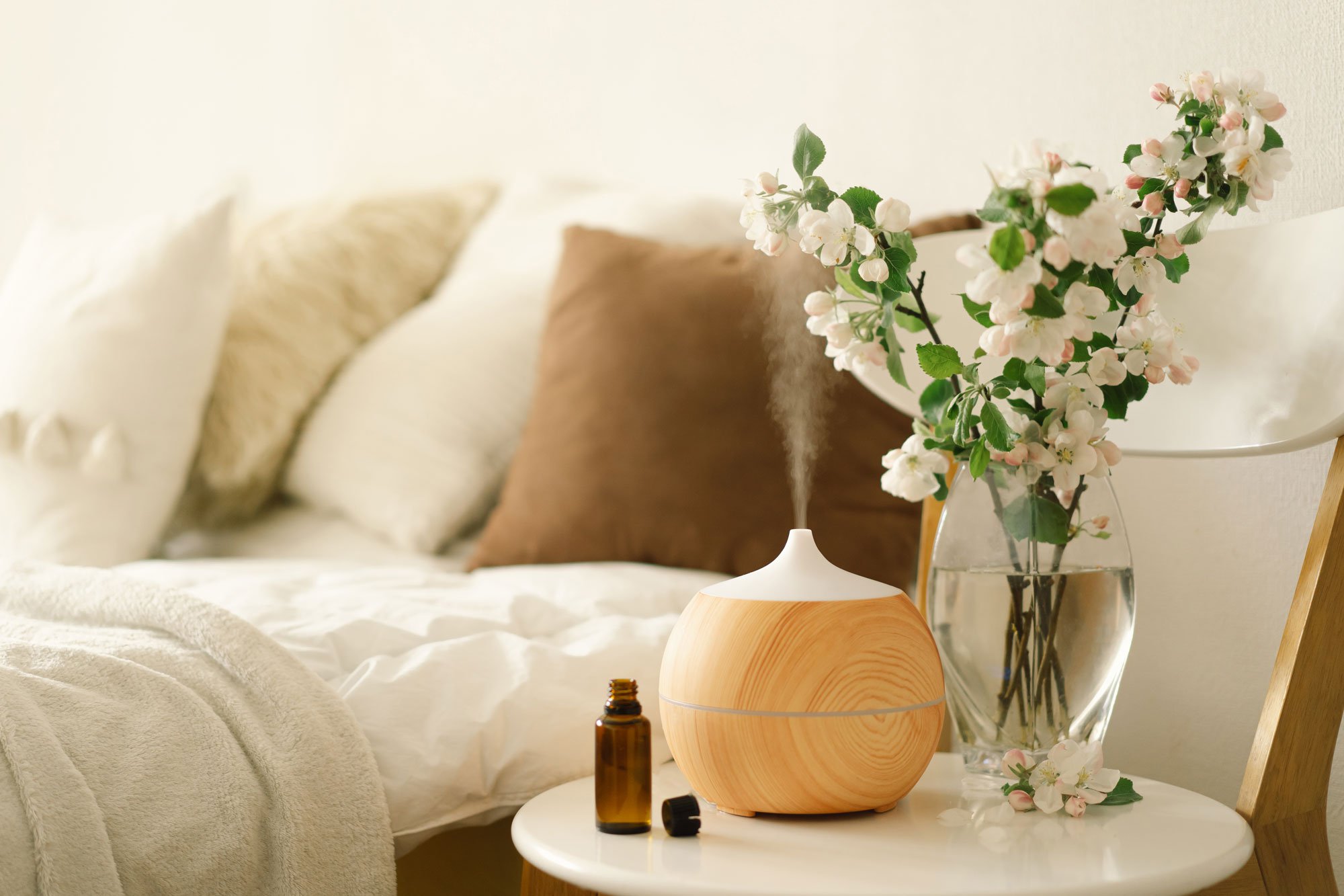 Essential oil diffuser and essential oils on chair next to bed