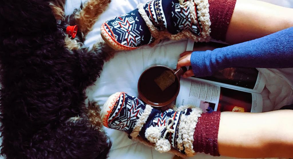 Person reading a magazine with a cup of tea wearing comfortable socks