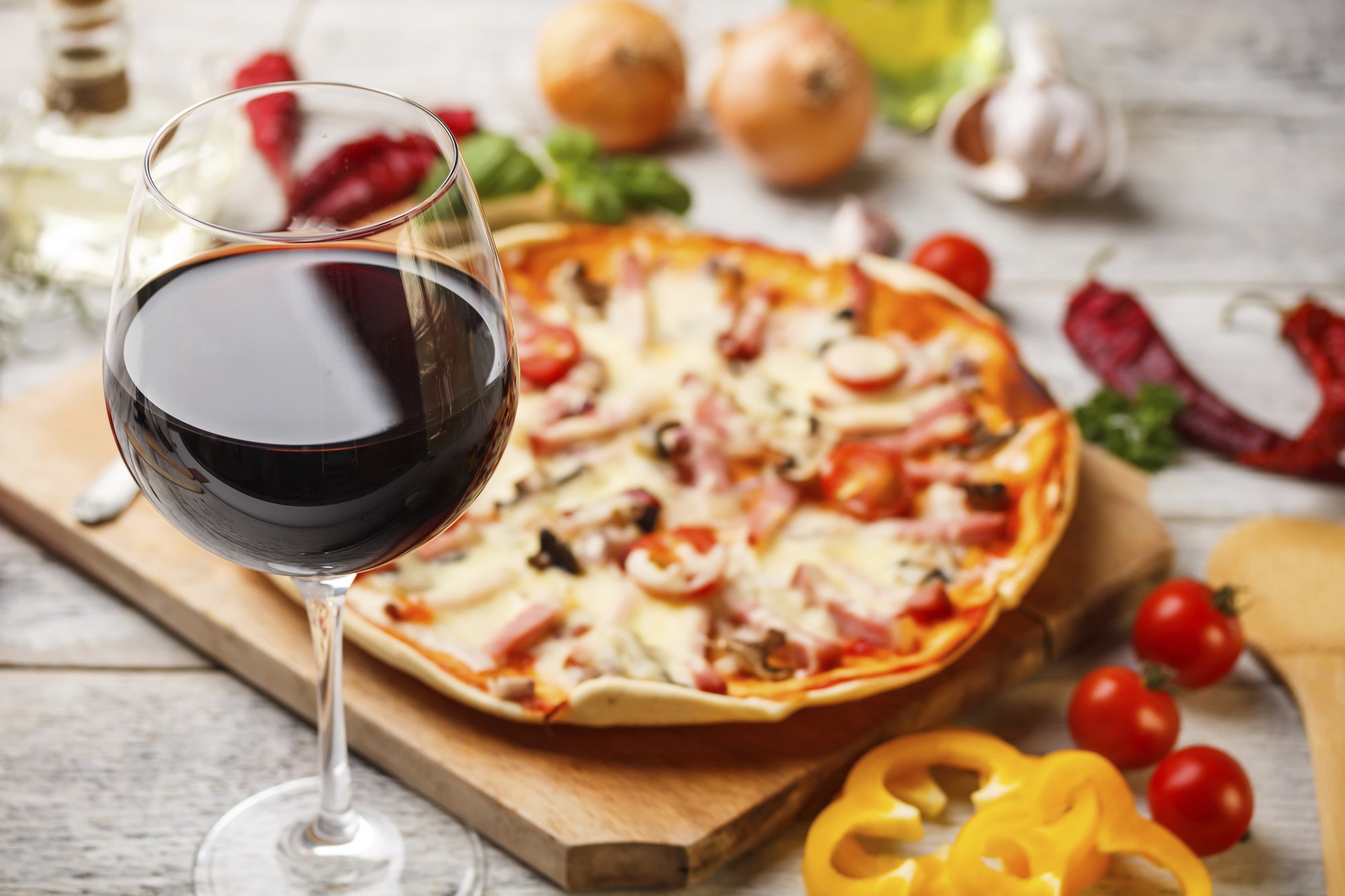 Glass of red wine with homemade pizza in the background