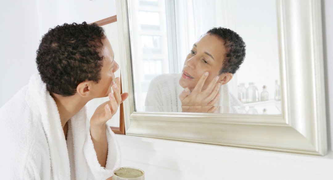 African American woman applying face mask.