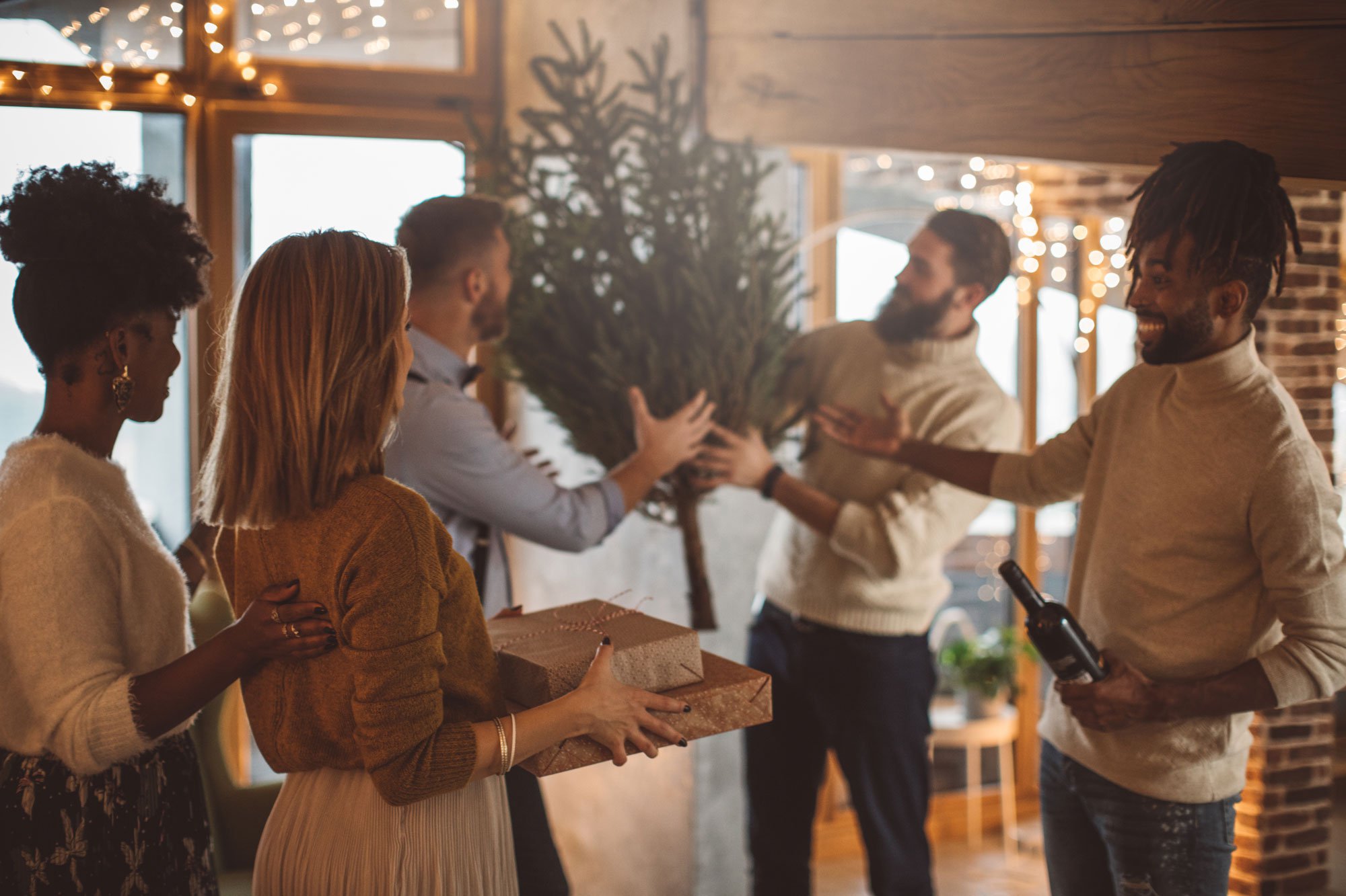 Group of friends gathered at home for the holidays hugging and holiday presents