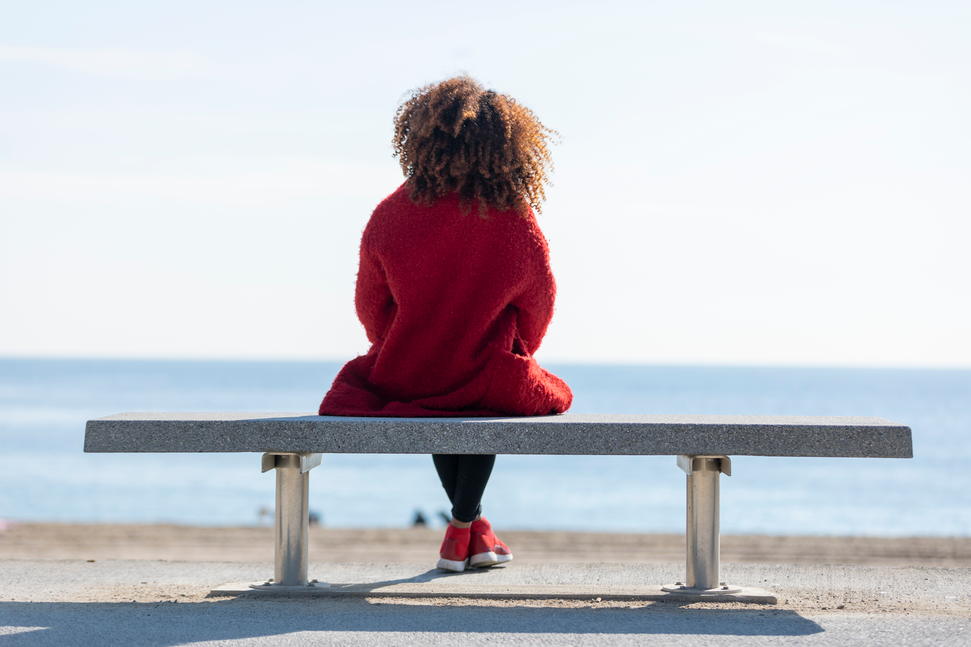 Woman sitting on park bench overlooking the ocean