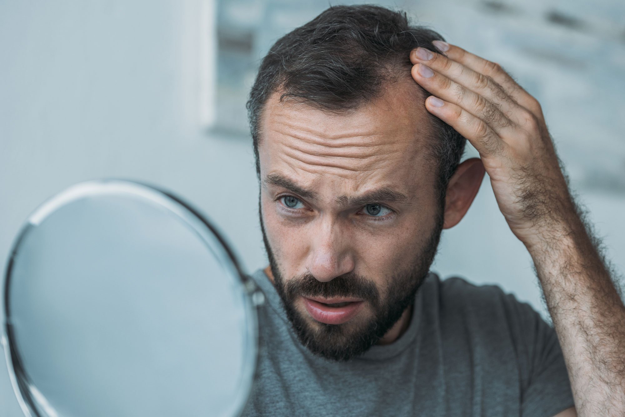 Man looking at hair in mirror