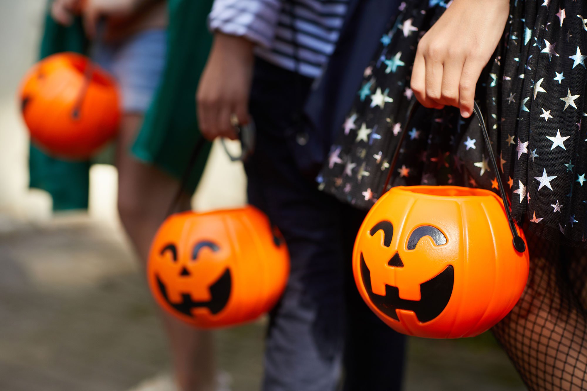 Close up of kids hands holding halloween trick-or-treating bags