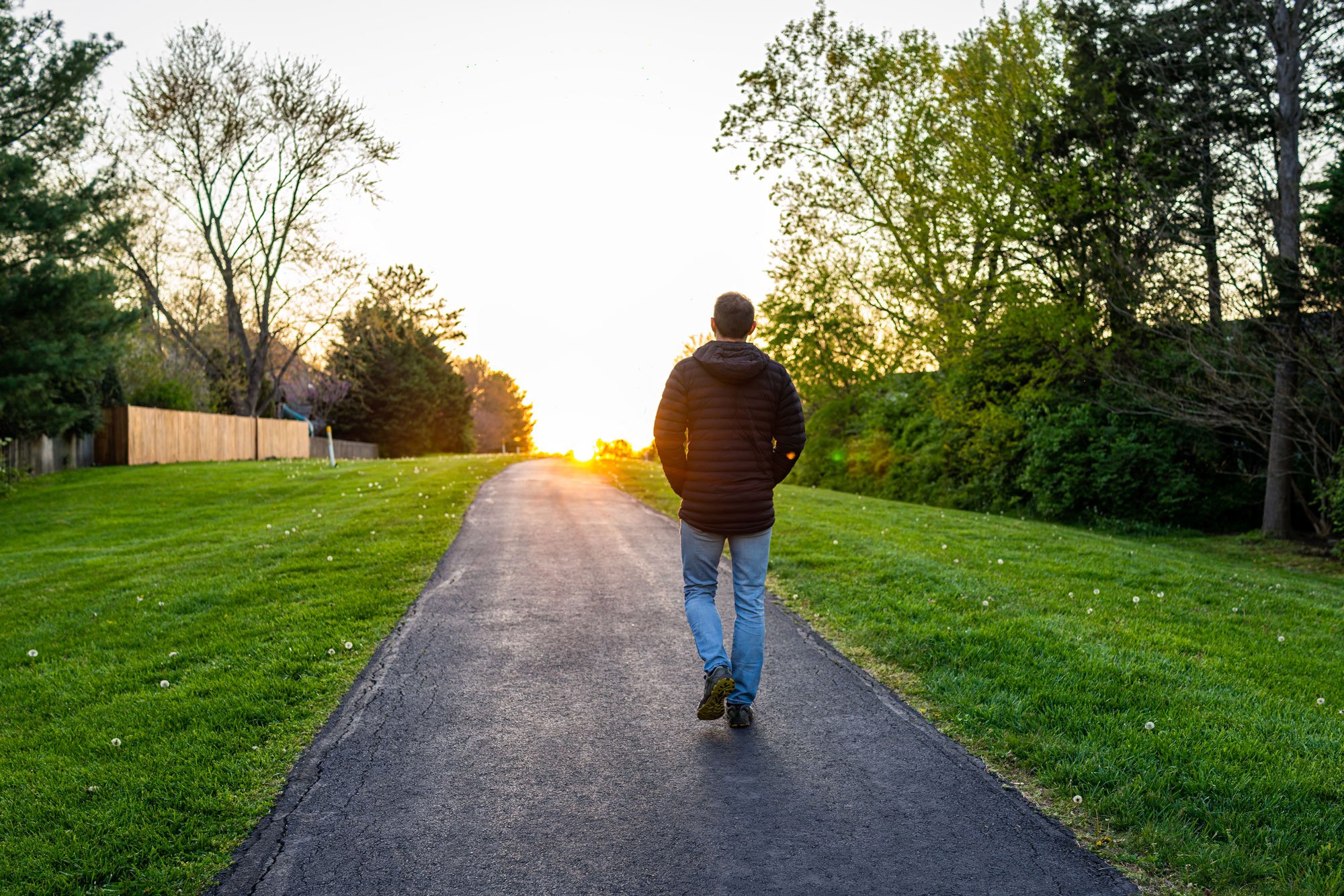 Man walking on a trail towards the sunset