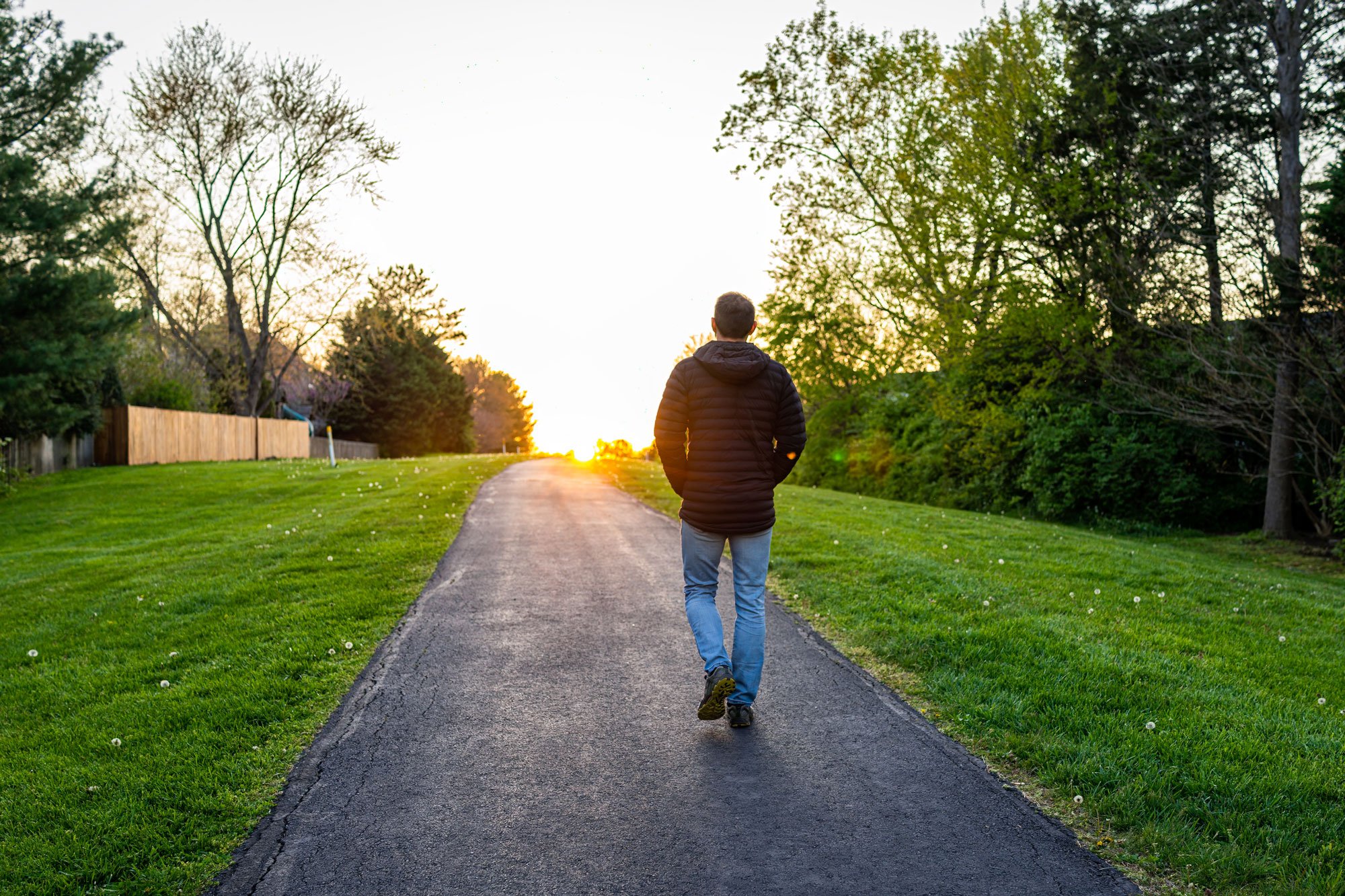 Man walking on a trail towards the sunset