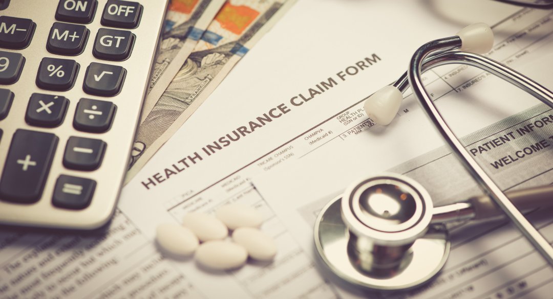 Close up of health insurance claim form, stethoscope, and calculator