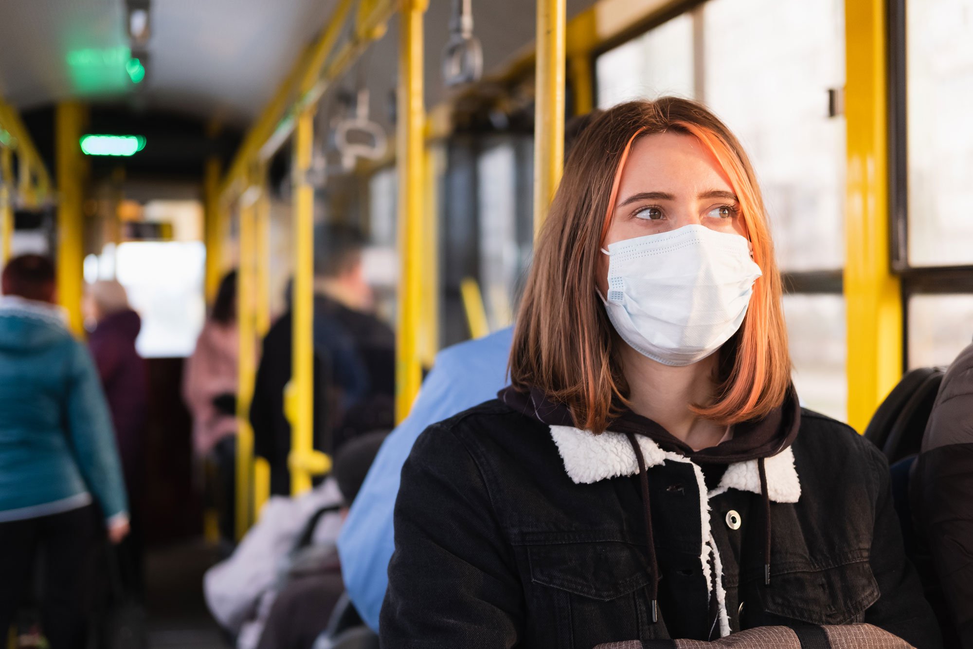 Young women sitting on bus wearing a mask