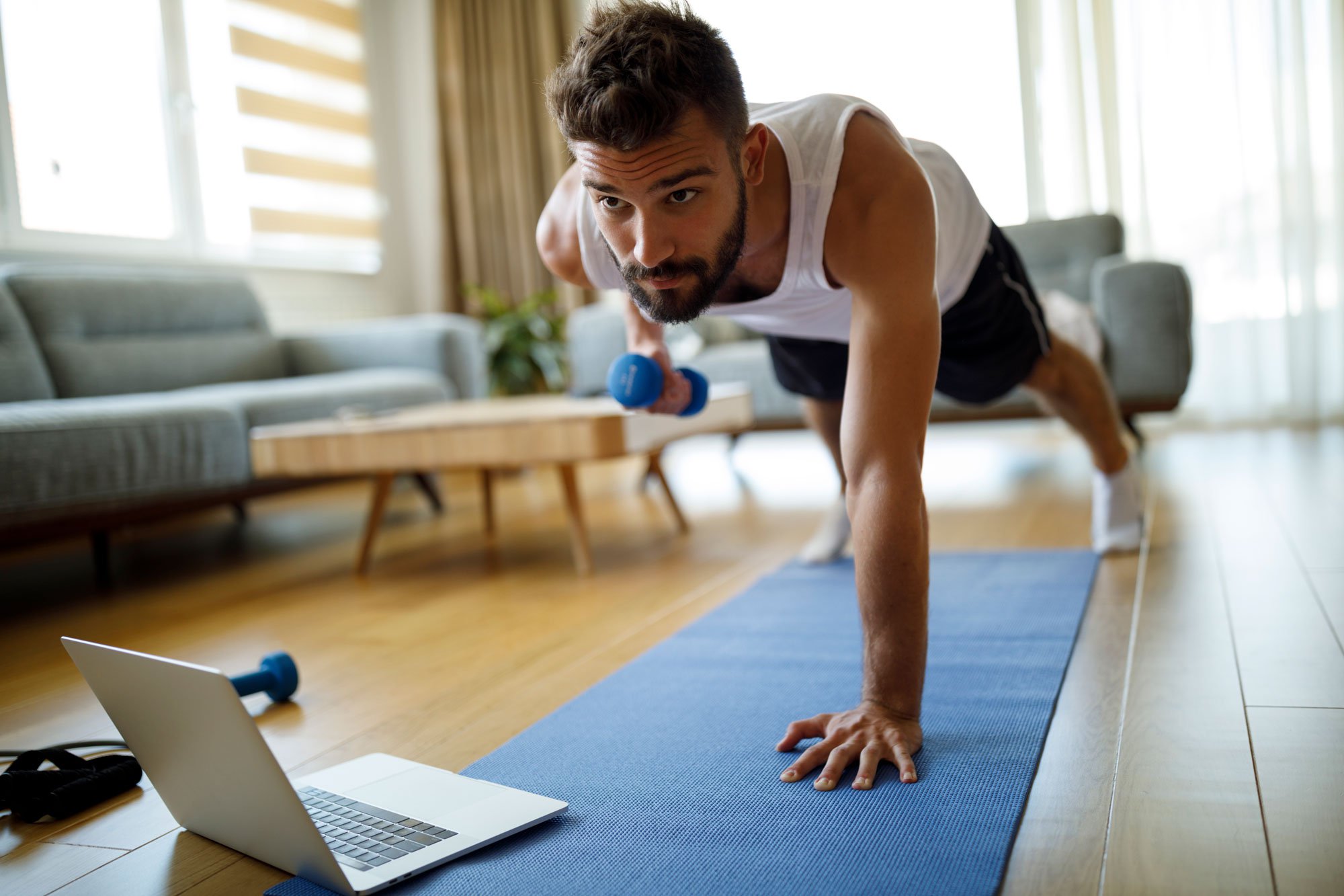 Man doing plank row exercise with dumbbell at home