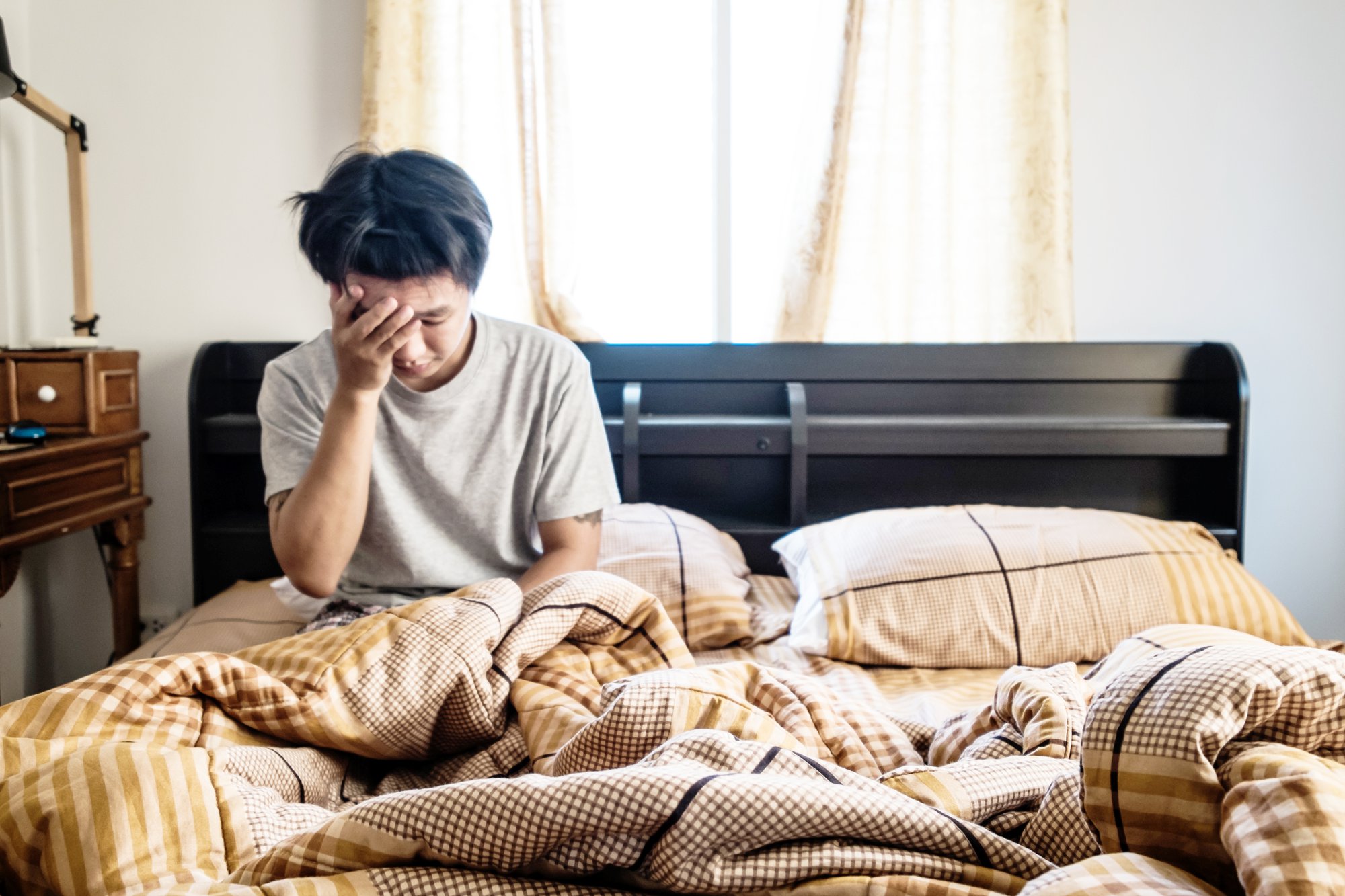 Man sitting in bed with his head in his hands