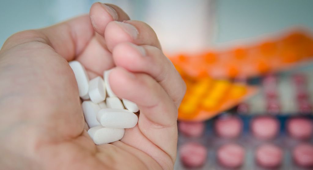 Person holding a handful of white pills