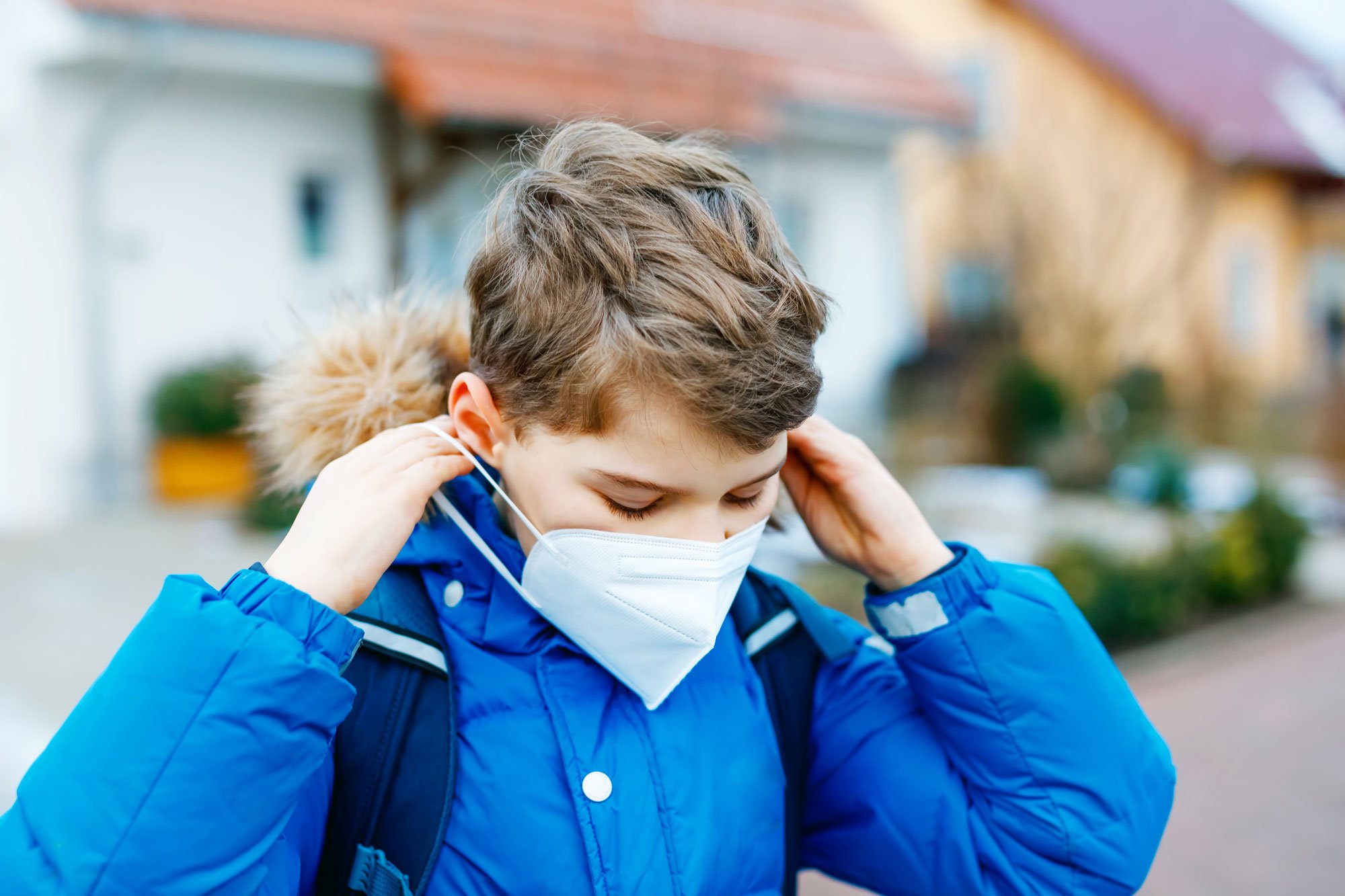 Young boy putting on an N95 mask