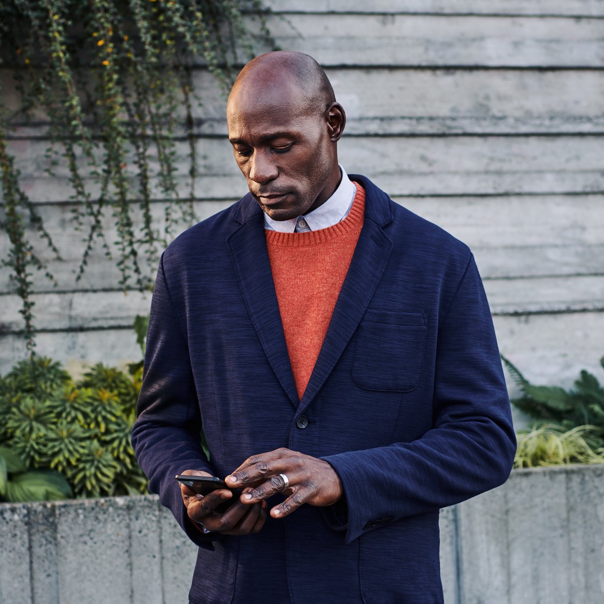 A man standing outside looking at a mobile device