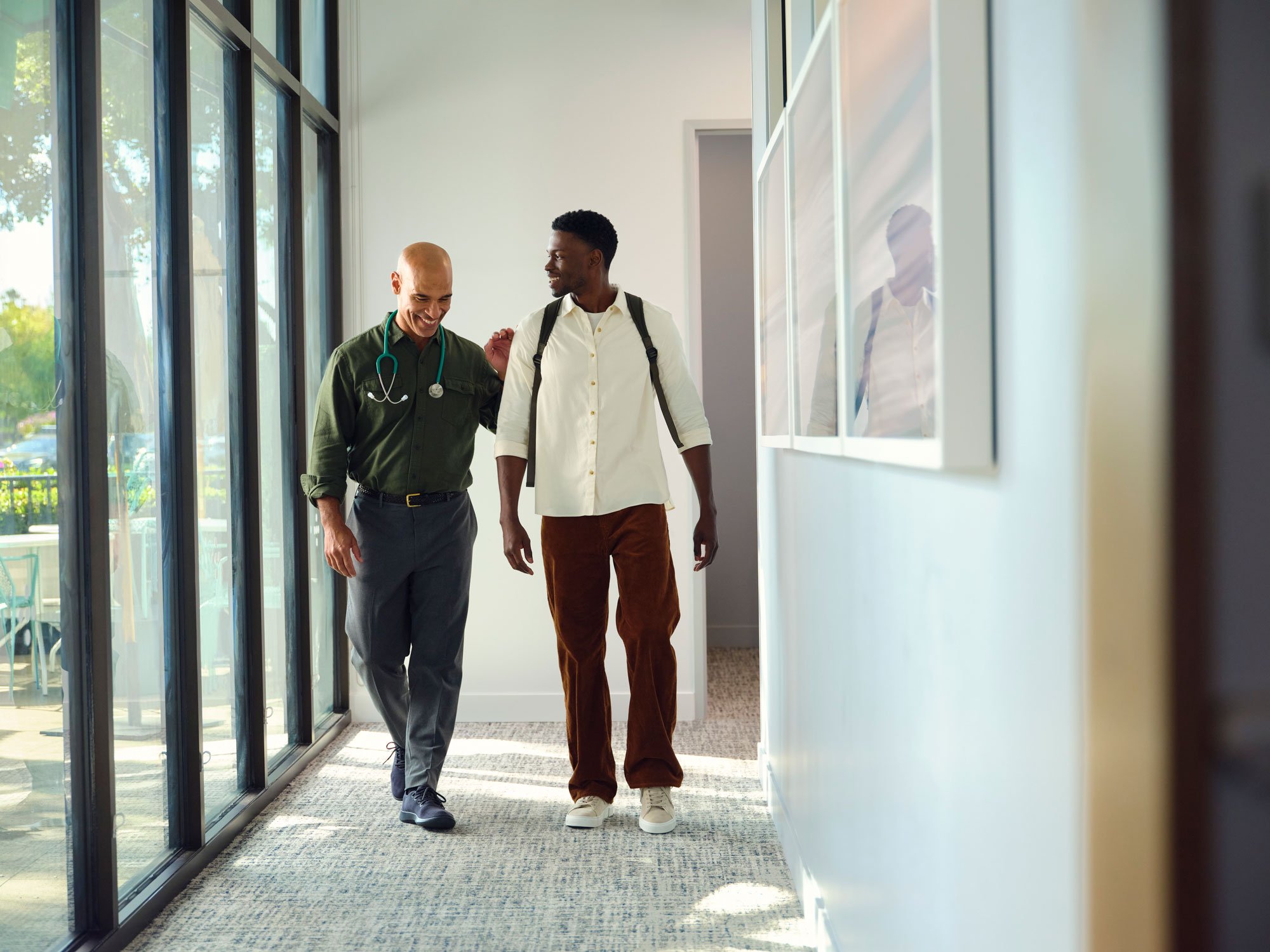 Doctor and male patient walking together down a One Medical office hallway