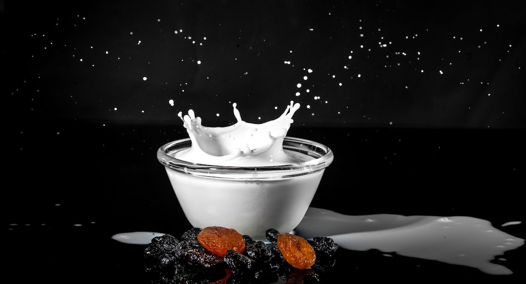 Cup of milked splashed after fruit dropped in