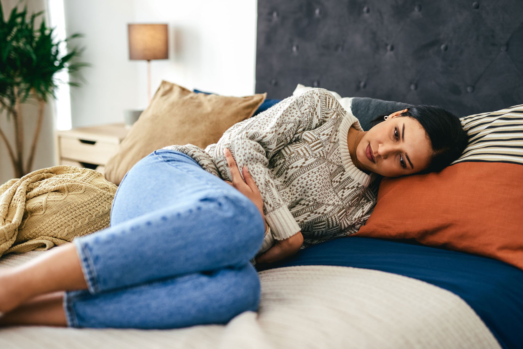 Woman laying on side holding her stomach in pain