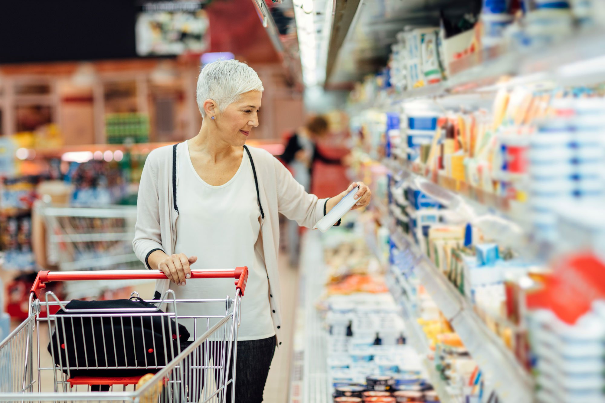 Woman reading nutrition label on dairy product at the grocery store