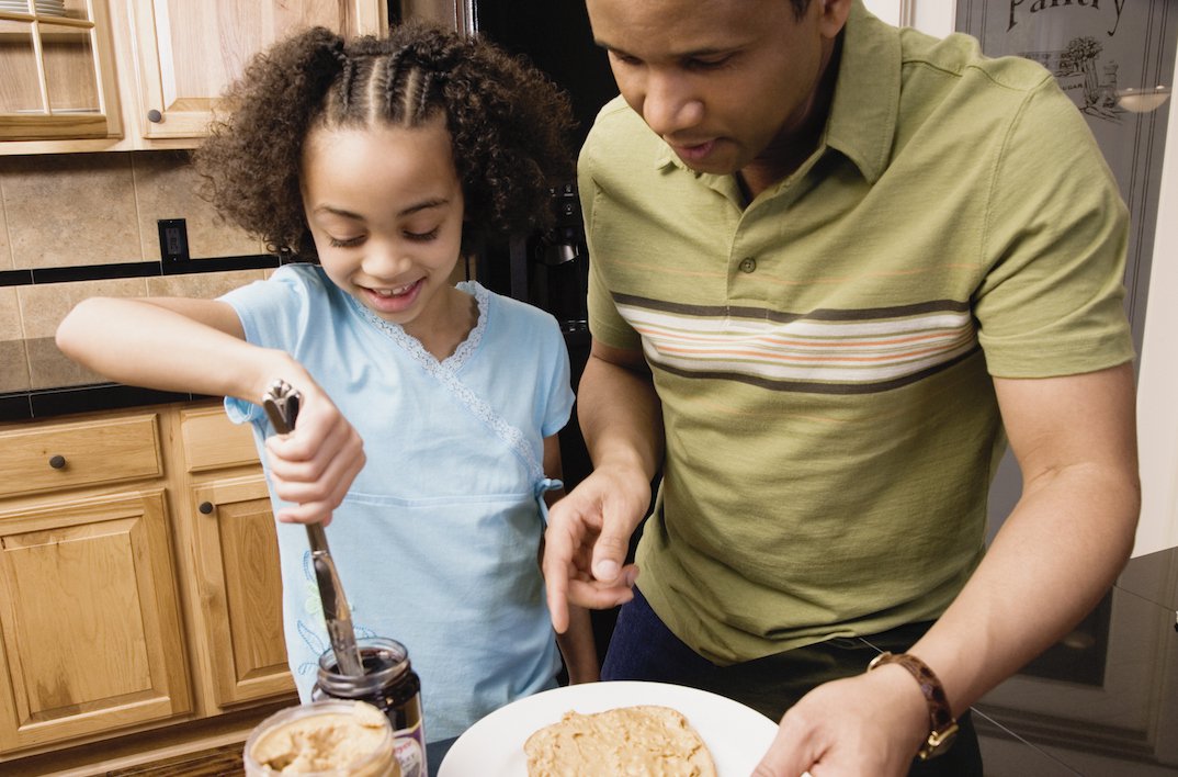 African father and daughter making peanut butter and jelly sandwich