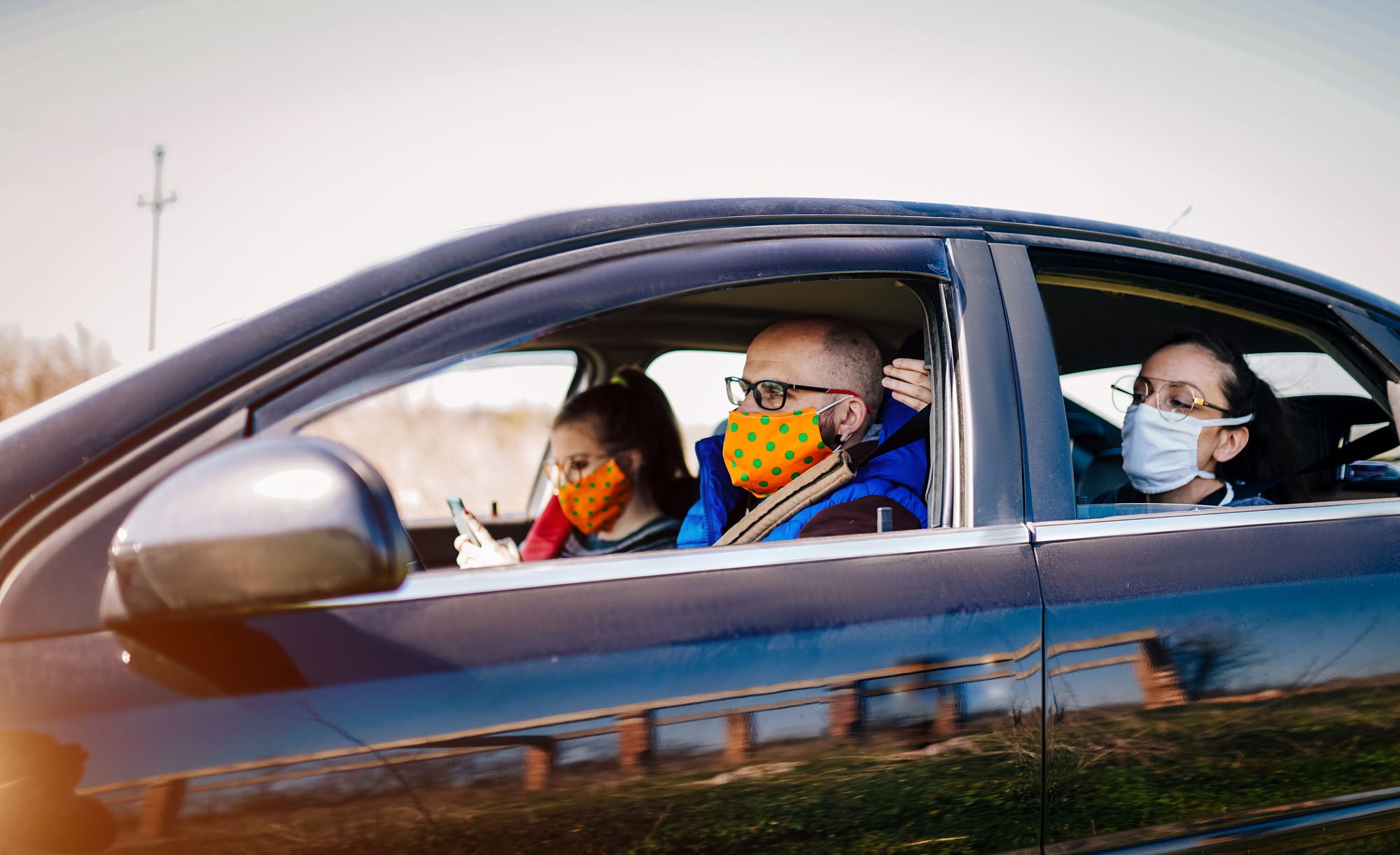 People in a car wearing clinical masks