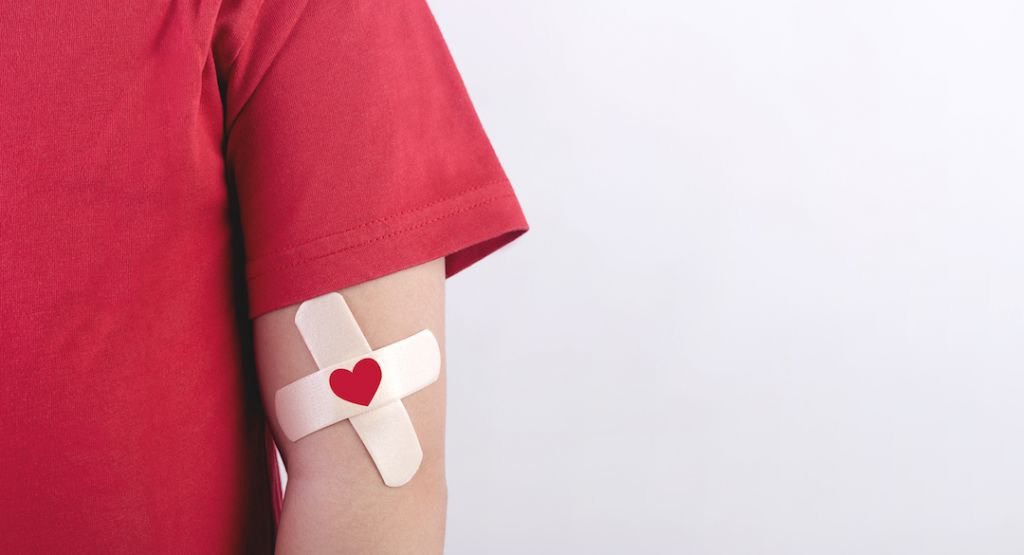 Close up of a person's arm with bandaid and heart