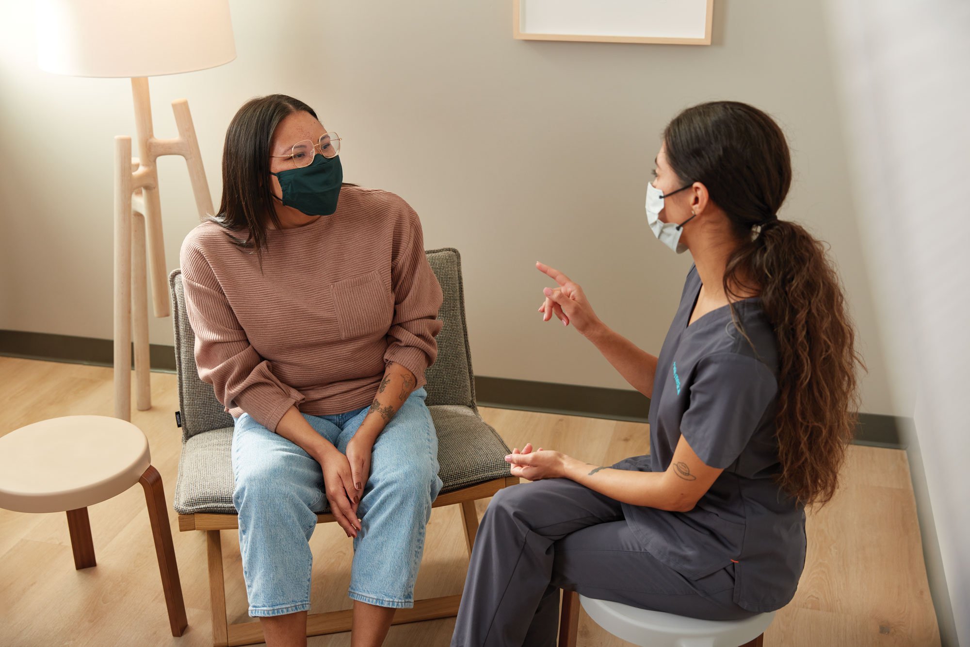 Young woman sitting in doctor's office talking with provider