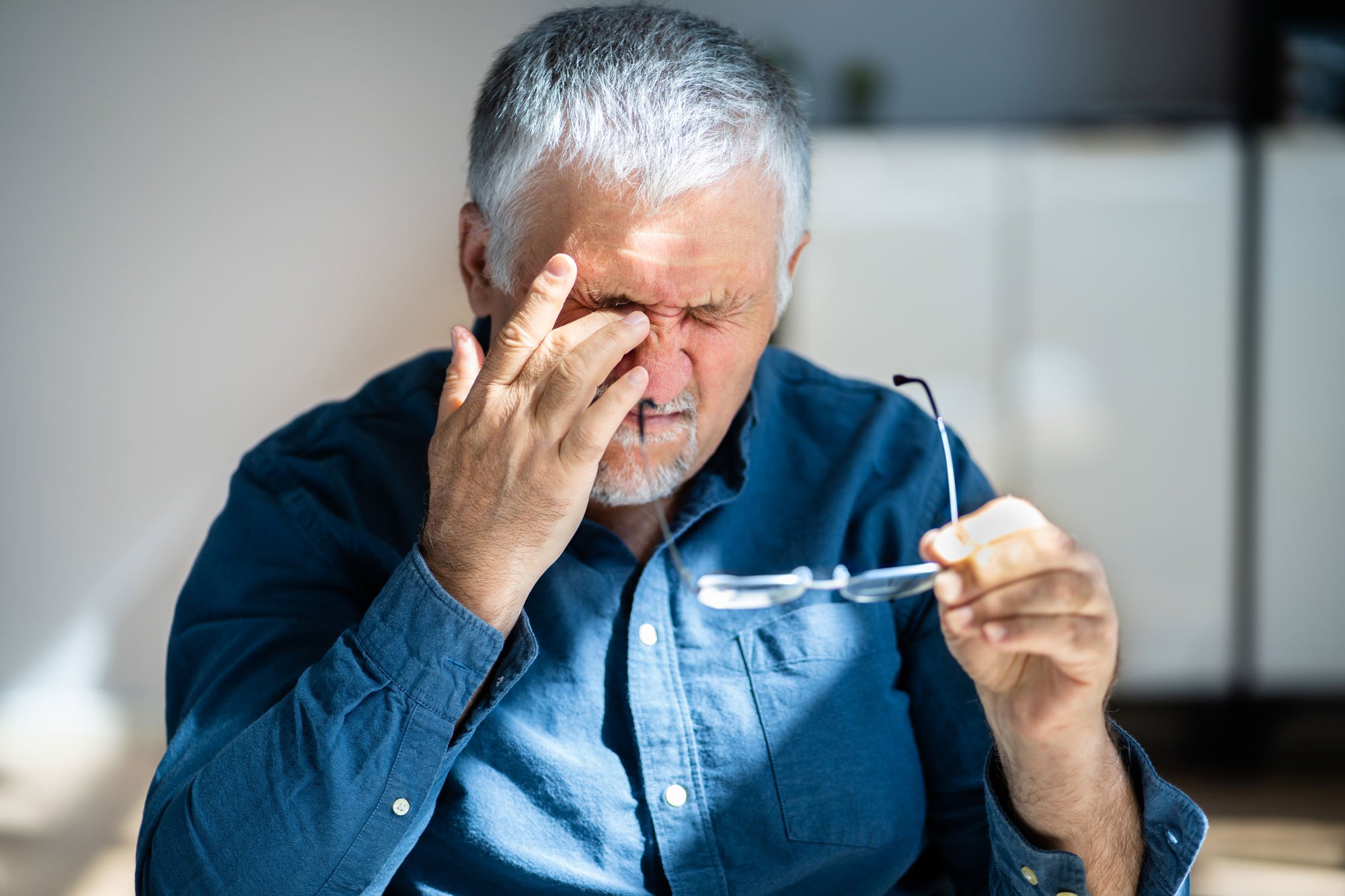 Older man rubbing his eye