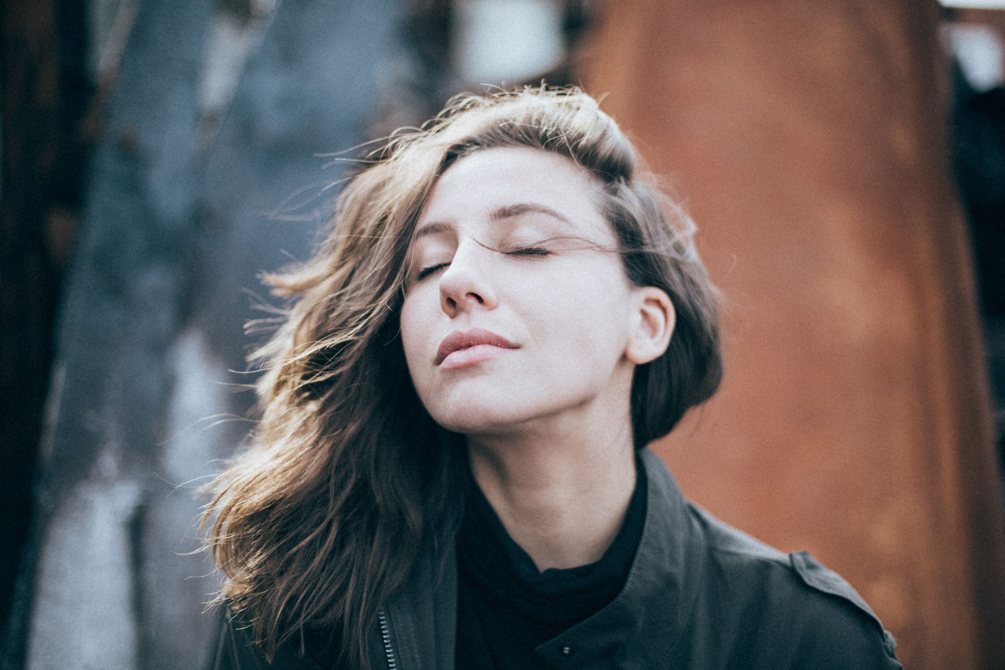 Woman with eyes closed and hair blowing around her.