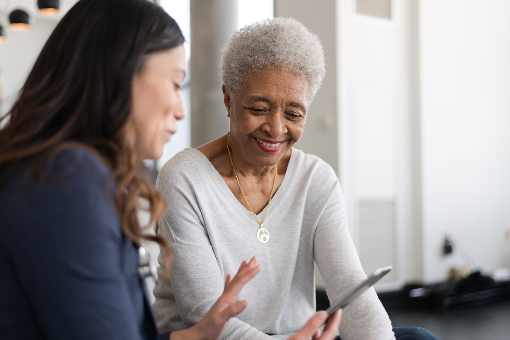 Young female doctor talking to elderly female patient