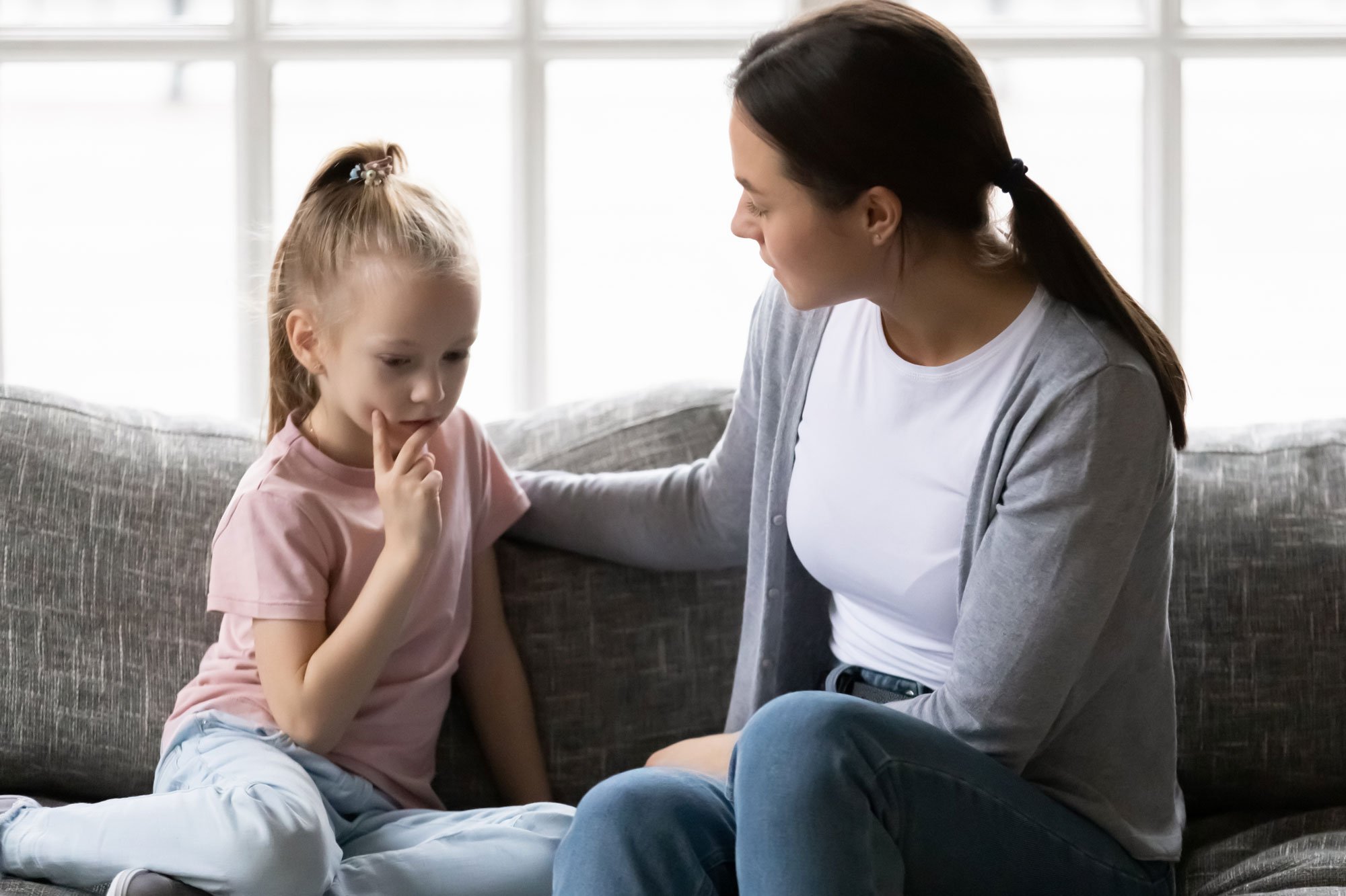 Mom comforting upset young daughter on the couch