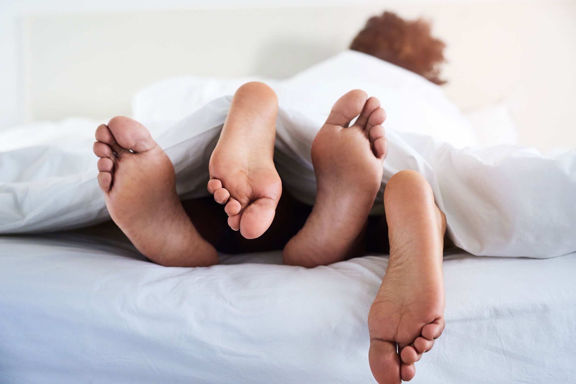 Photo of a couple's feet poking out from under the sheets
