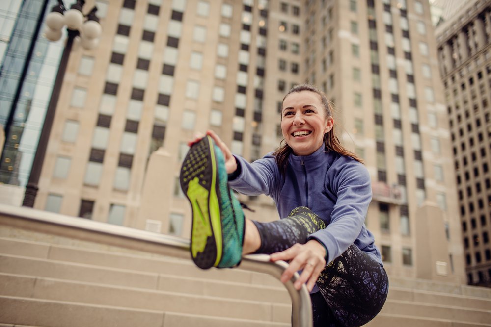 Woman stretching with a city in the background