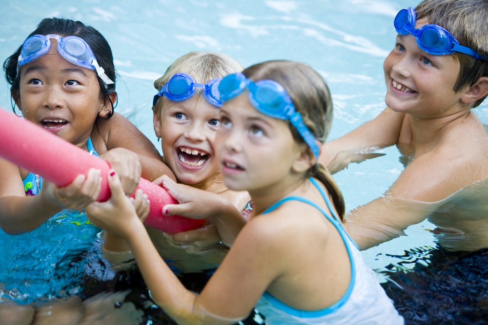 Group of children in a pool playing with a pool noodle