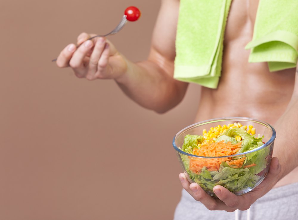 Muscular person holding a bowl of salad