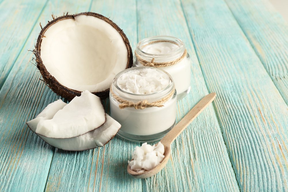 Cracked coconut sitting next to jars of coconut