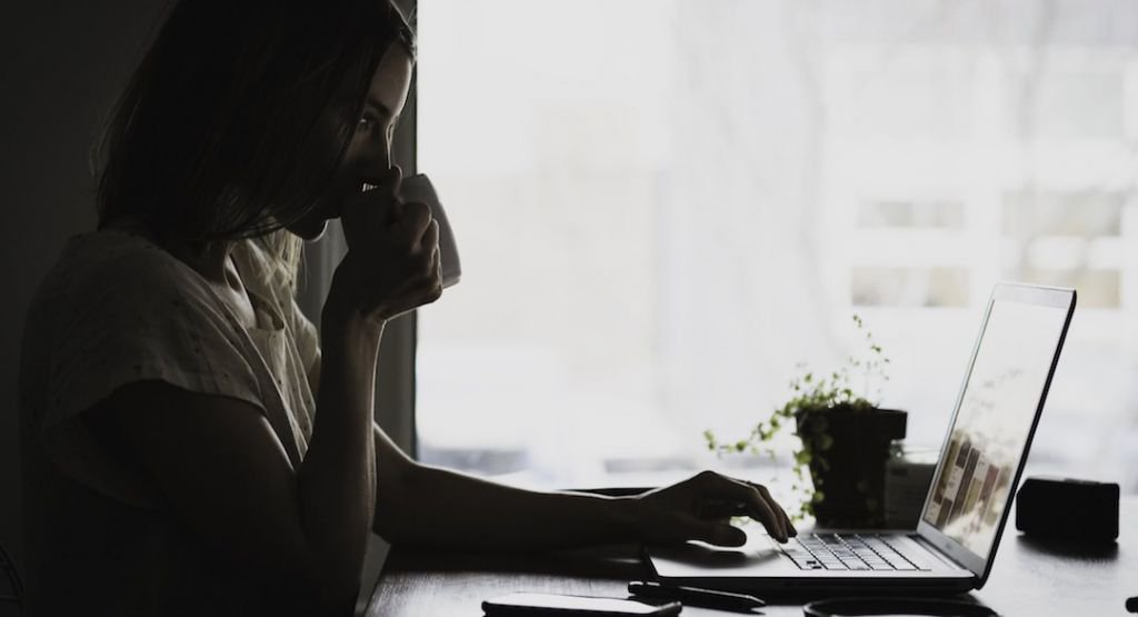 Woman drinking coffee and looking at a computer