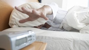 Hand reaching out to snooze the alarm