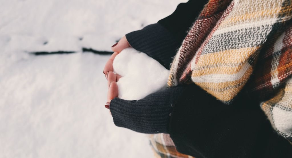 Hands holding snow in the shape of a heart