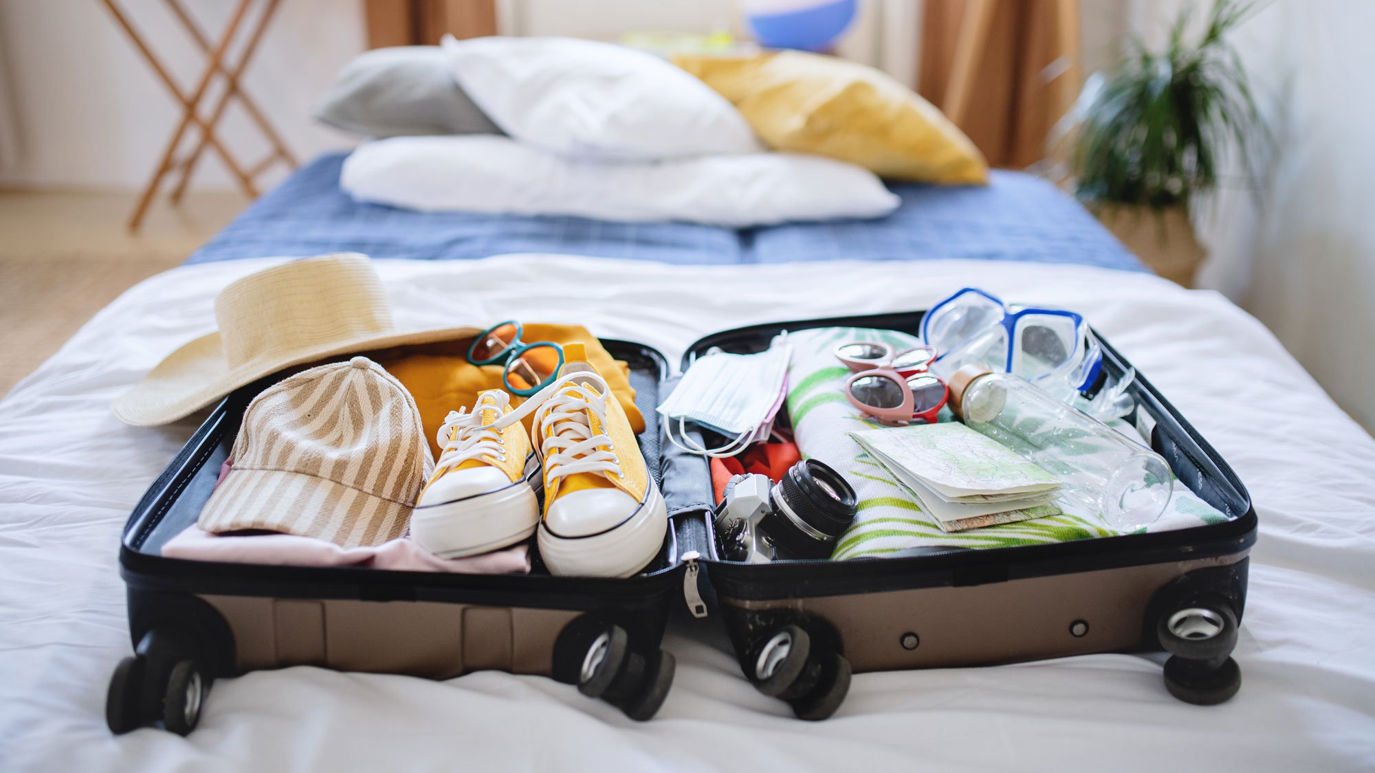 An open suitcase on the bed being packed for summer vacation