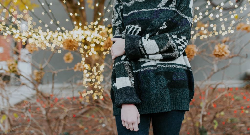 Person wearing sweater and holding right arm