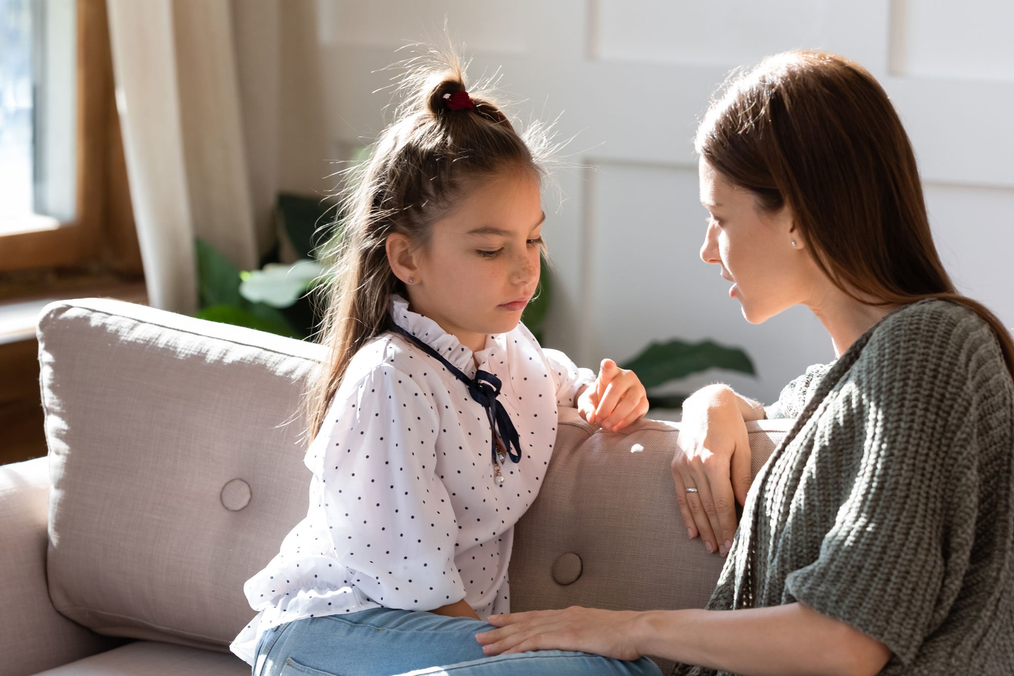 Mother talking to daughter on couch