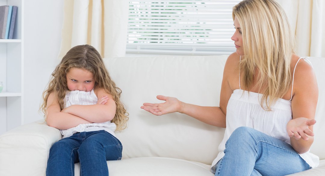 Angry mother sitting with her daughter on the sofa