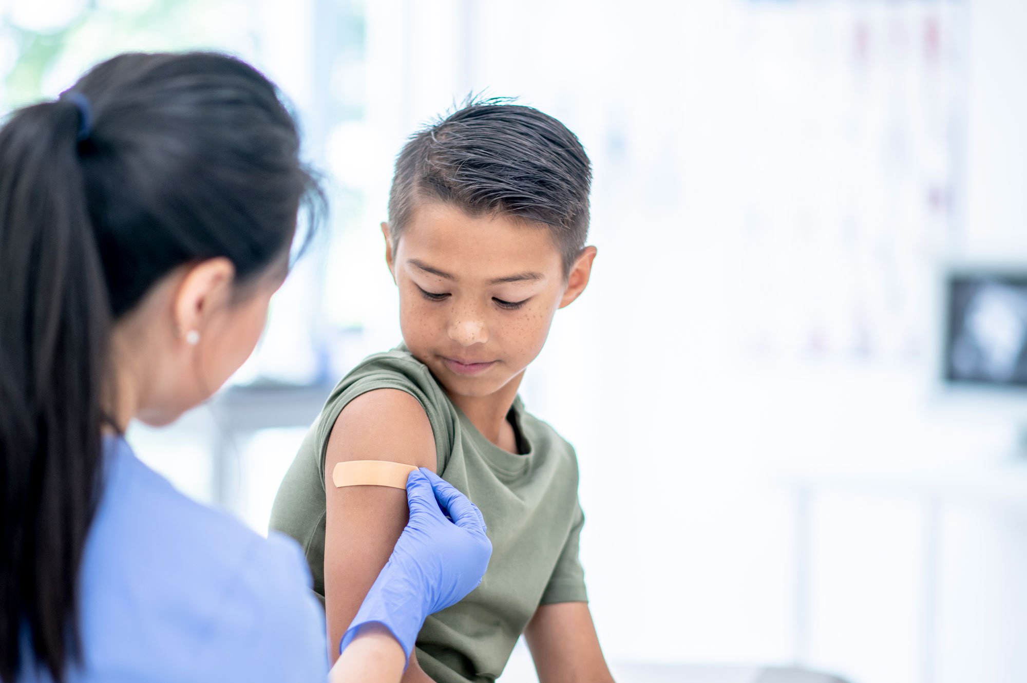 Doctor putting bandaid on young boy patient