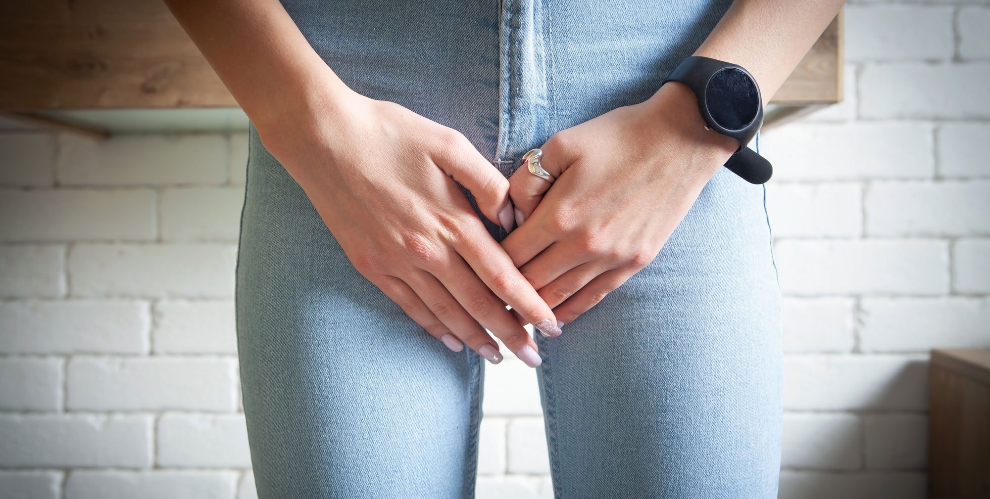 Women holding hands in front of crotch