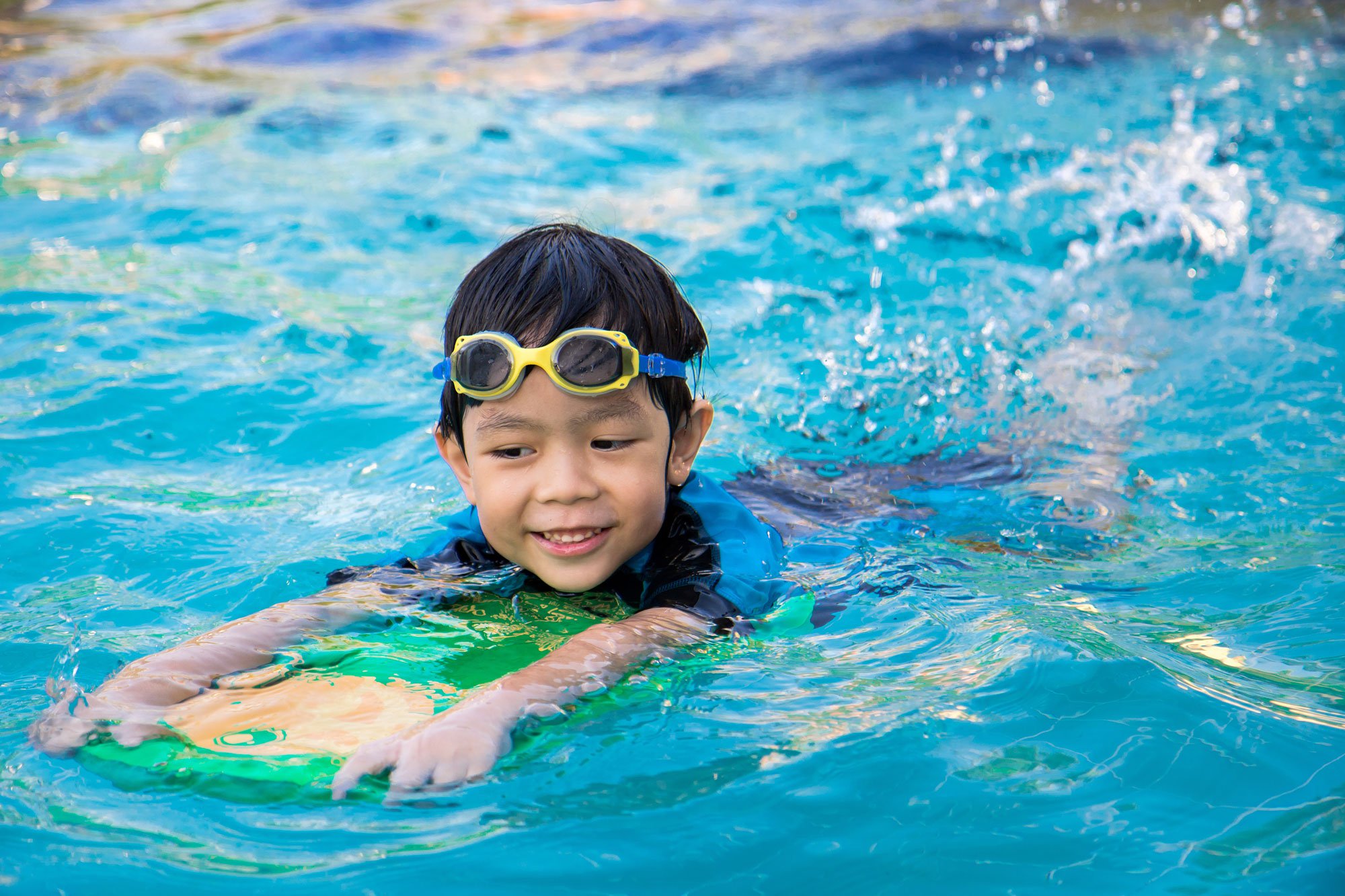 Boy using a kick board in a pool