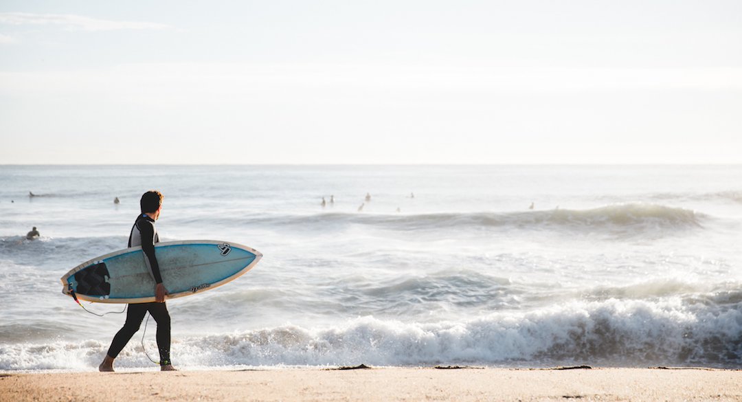 Man with a surfboard looking out at ocean