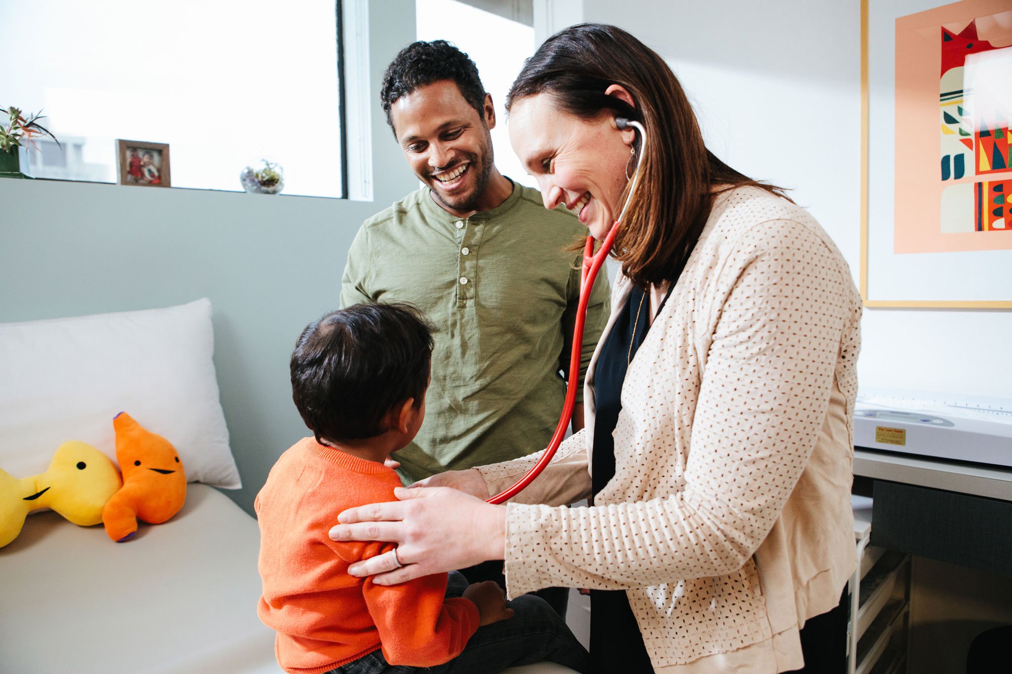 Female pediatrician using stethoscope to examine young boy patient during well-child visit