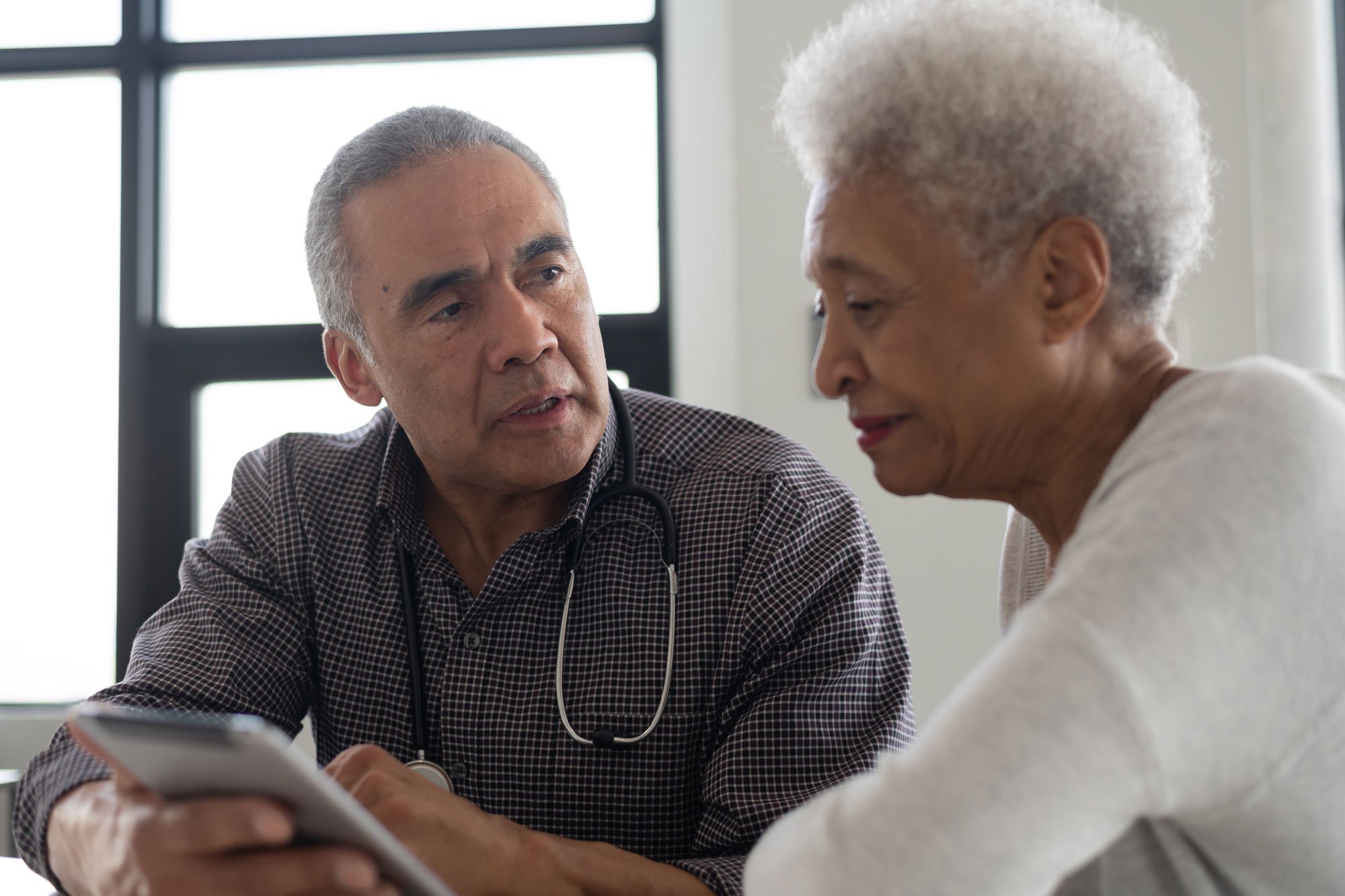 Male doctor talking to his elderly female patient in her home.