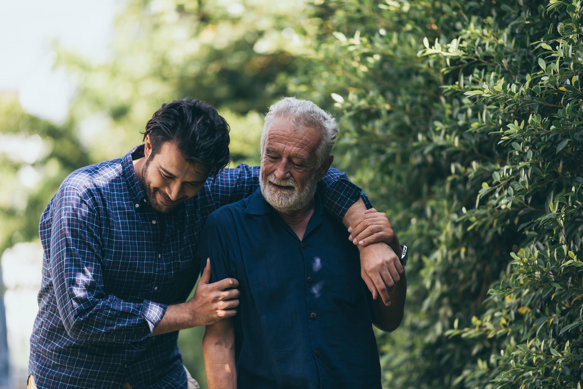 Older man and son walking through the park