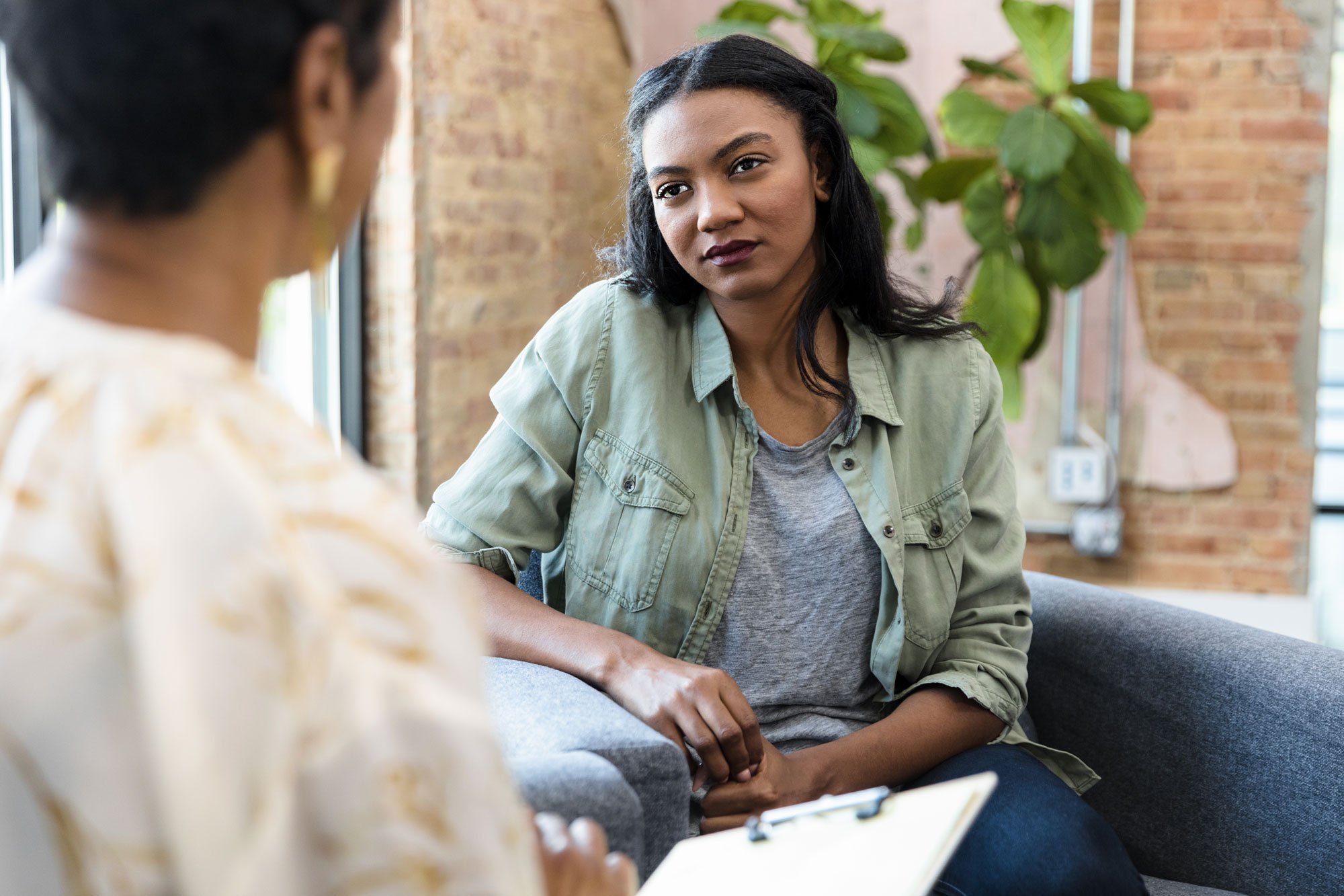 Woman sitting in chair talking to doctor with clipboard